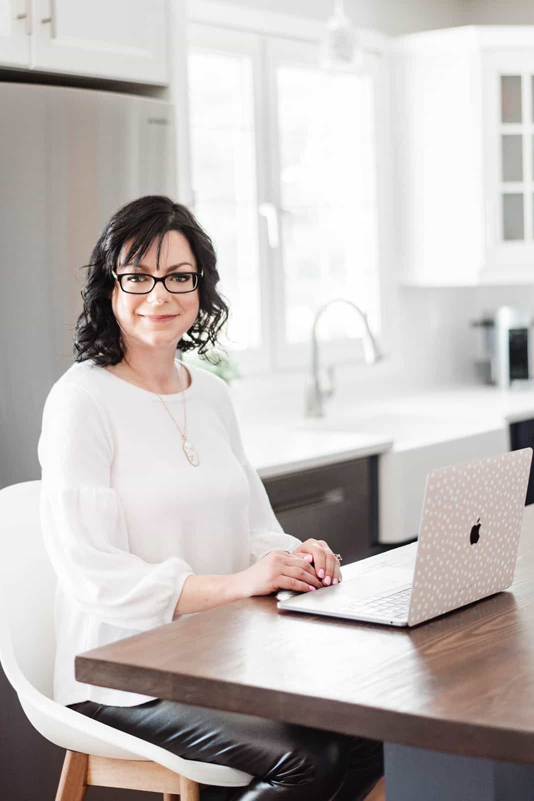 Food blogger Stacie Vaughan sitting at a table with a laptop.