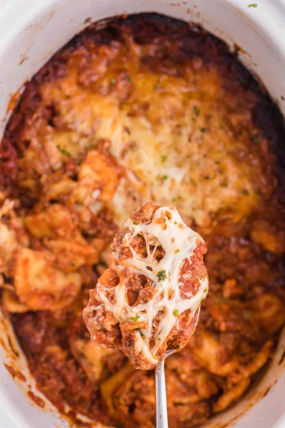 Slow Cooker Ravioli Lasagna - This Lazy Lasagna is a super easy Crockpot recipe made with frozen ravioli, homemade tomato sauce with beef and loads of cheese. You'll love all the cheesy, hearty layers. Plus, it's freezer friendly!