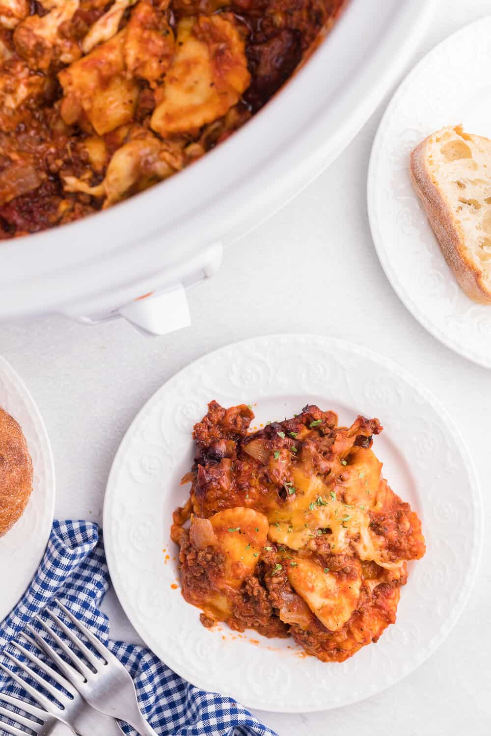 Slow Cooker Ravioli Lasagna - This Lazy Lasagna is a super easy Crockpot recipe made with frozen ravioli, homemade tomato sauce with beef and loads of cheese. You'll love all the cheesy, hearty layers. Plus, it's freezer friendly!