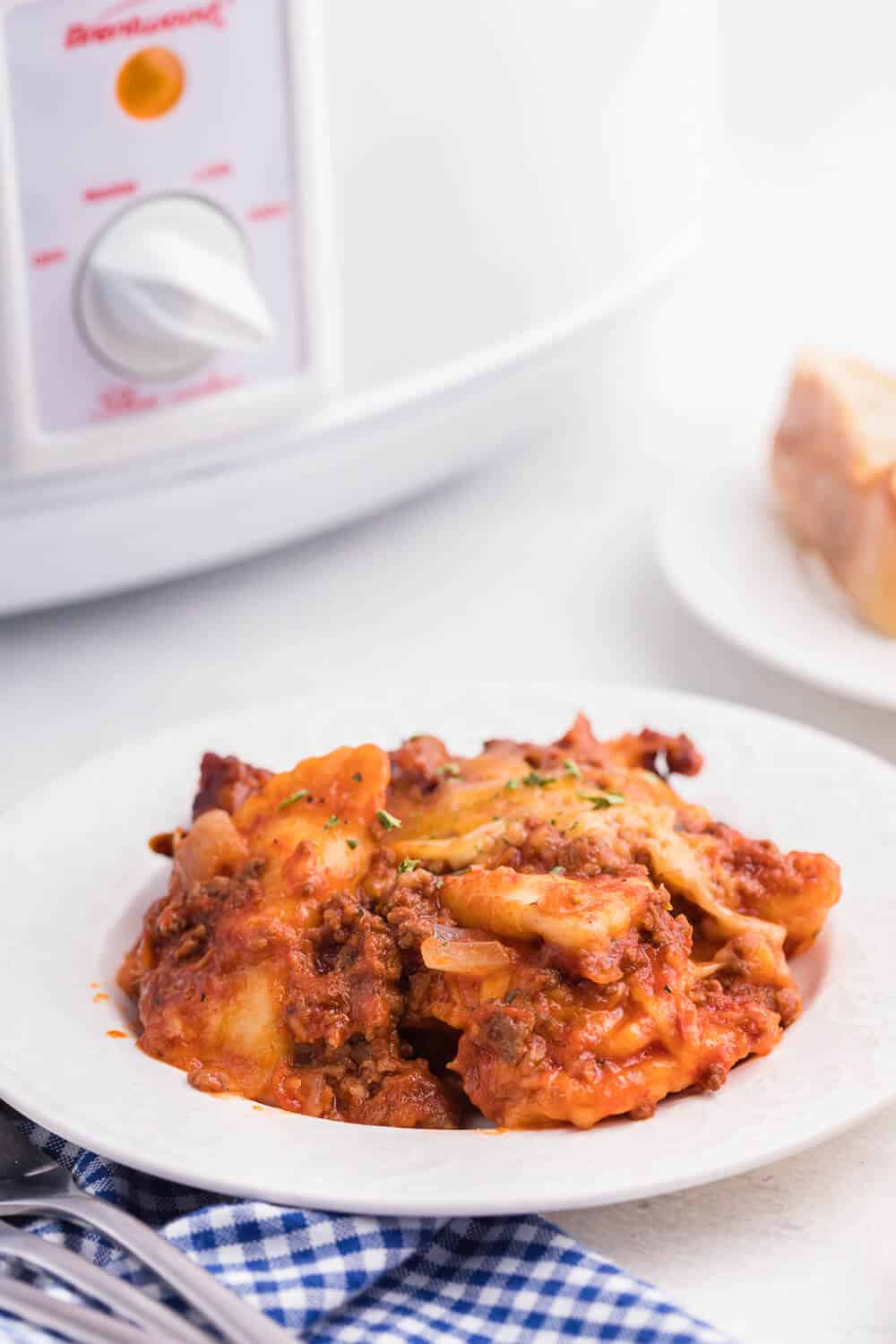 Slow Cooker Ravioli Lasagna - This Lazy Lasagna is a super easy Crockpot recipe made with frozen ravioli, homemade tomato sauce with beef and loads of cheese. You'll love all the cheesy, hearty layers. Plus, it's freezer friendly!