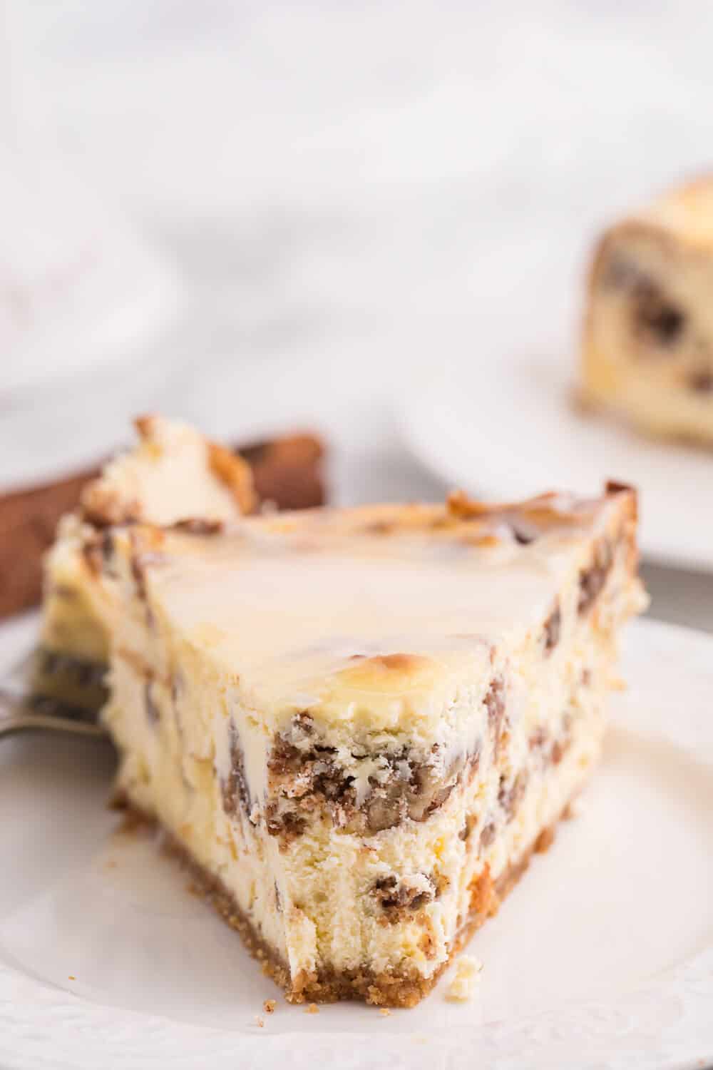 a slice of cinnamon roll cheesecake with a bite off the end