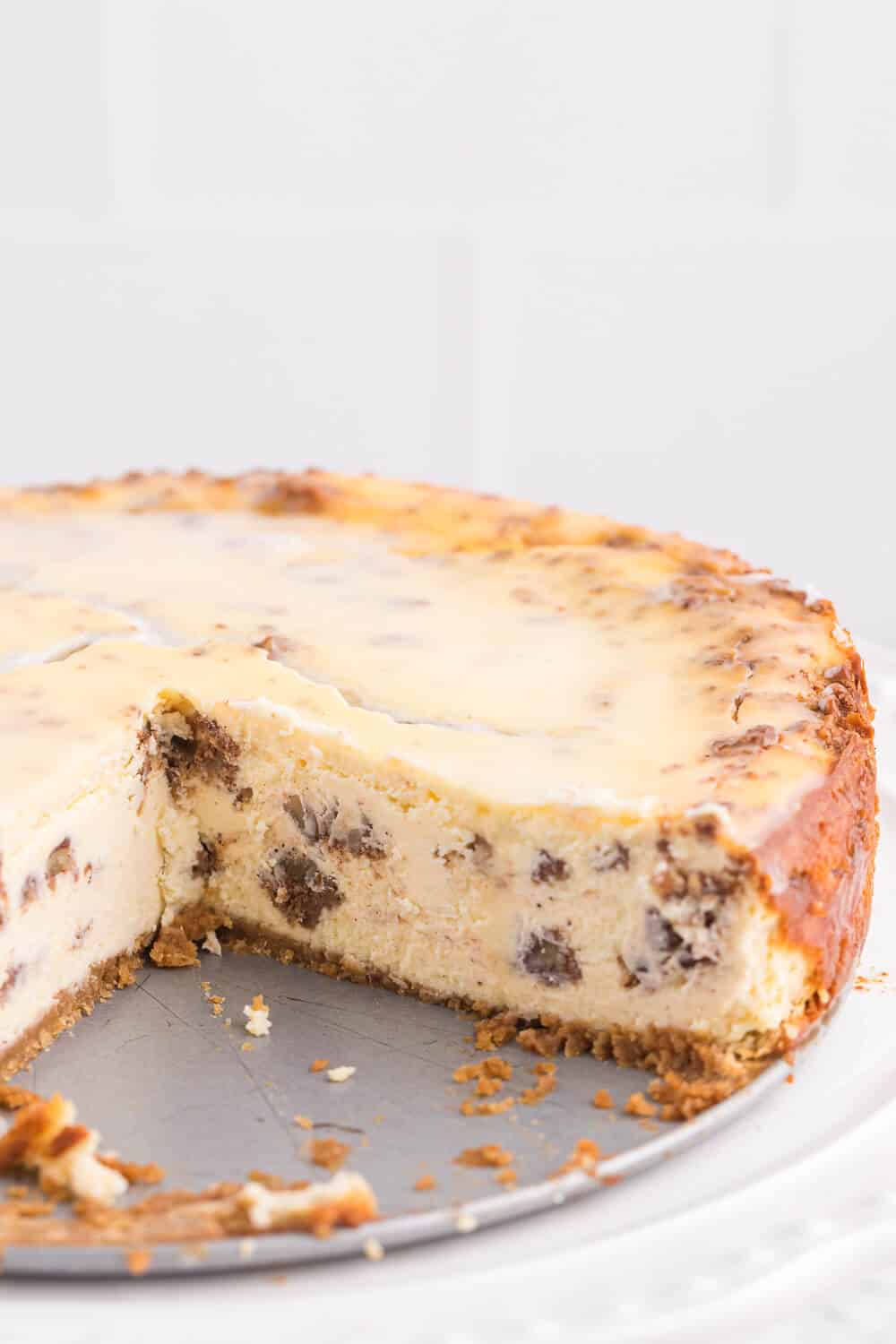 Whole cinnamon roll cheesecake with a few slices removed