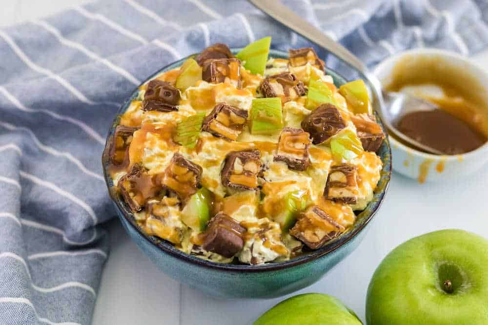 Snickers Salad Recipe - One of the best dessert salad recipes ever! This easy recipe is made with vanilla pudding, green apples, Cool Whip, caramel and loads of Snickers bars.