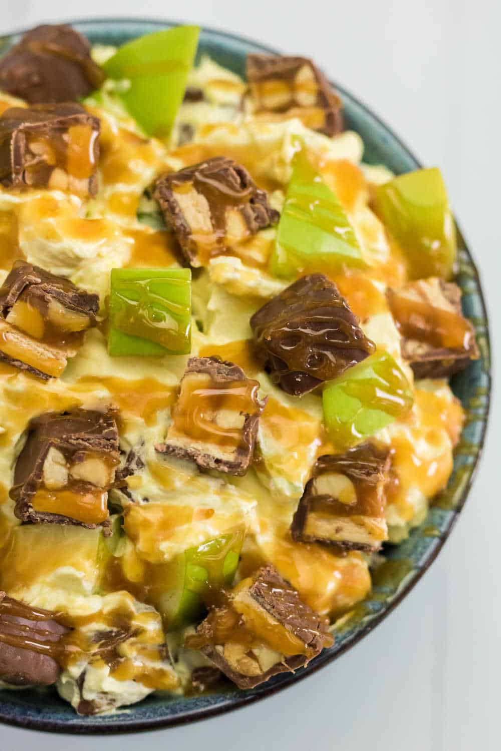 Snickers Salad Recipe - One of the best dessert salad recipes ever! This easy recipe is made with vanilla pudding, green apples, Cool Whip, caramel and loads of Snickers bars.