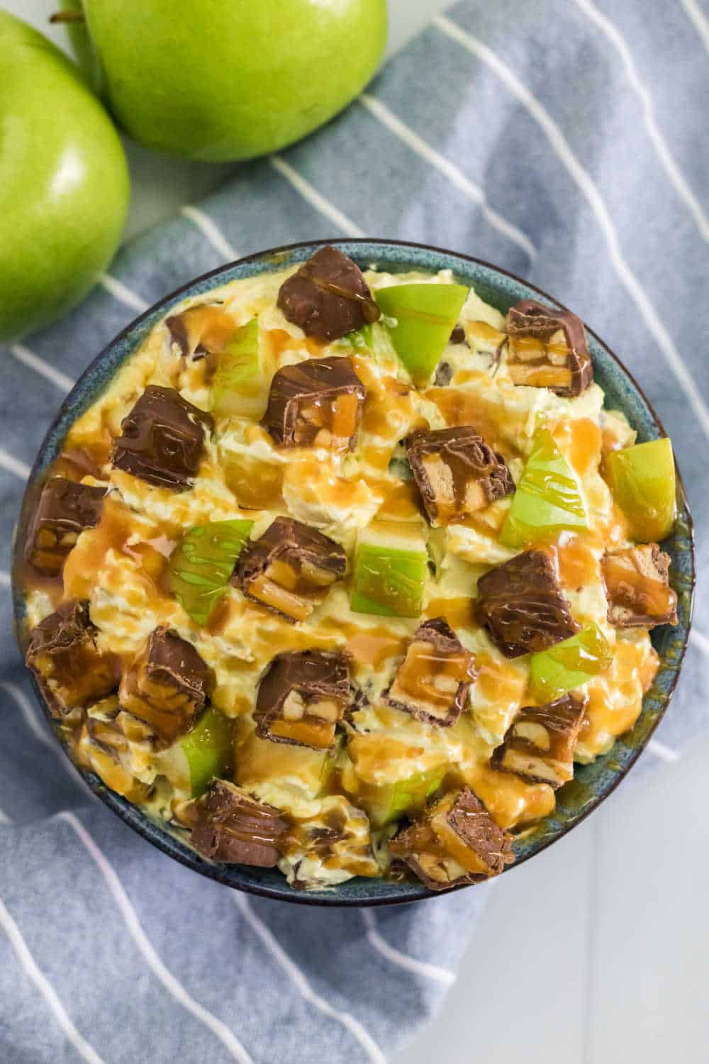 Snickers Salad Recipe - One of the best dessert salad recipes ever! This easy recipe is made with vanilla pudding, green apples, Cool Whip, caramel and loads of Snickers bars.