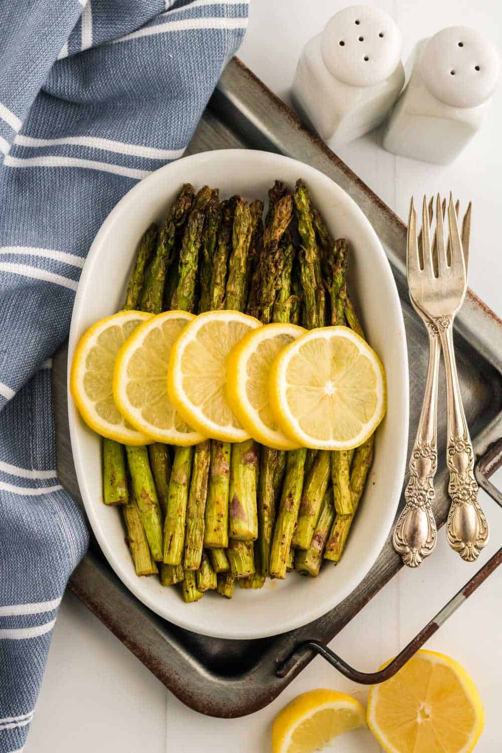 Asparagus topped with sliced lemon in a white casserole dish