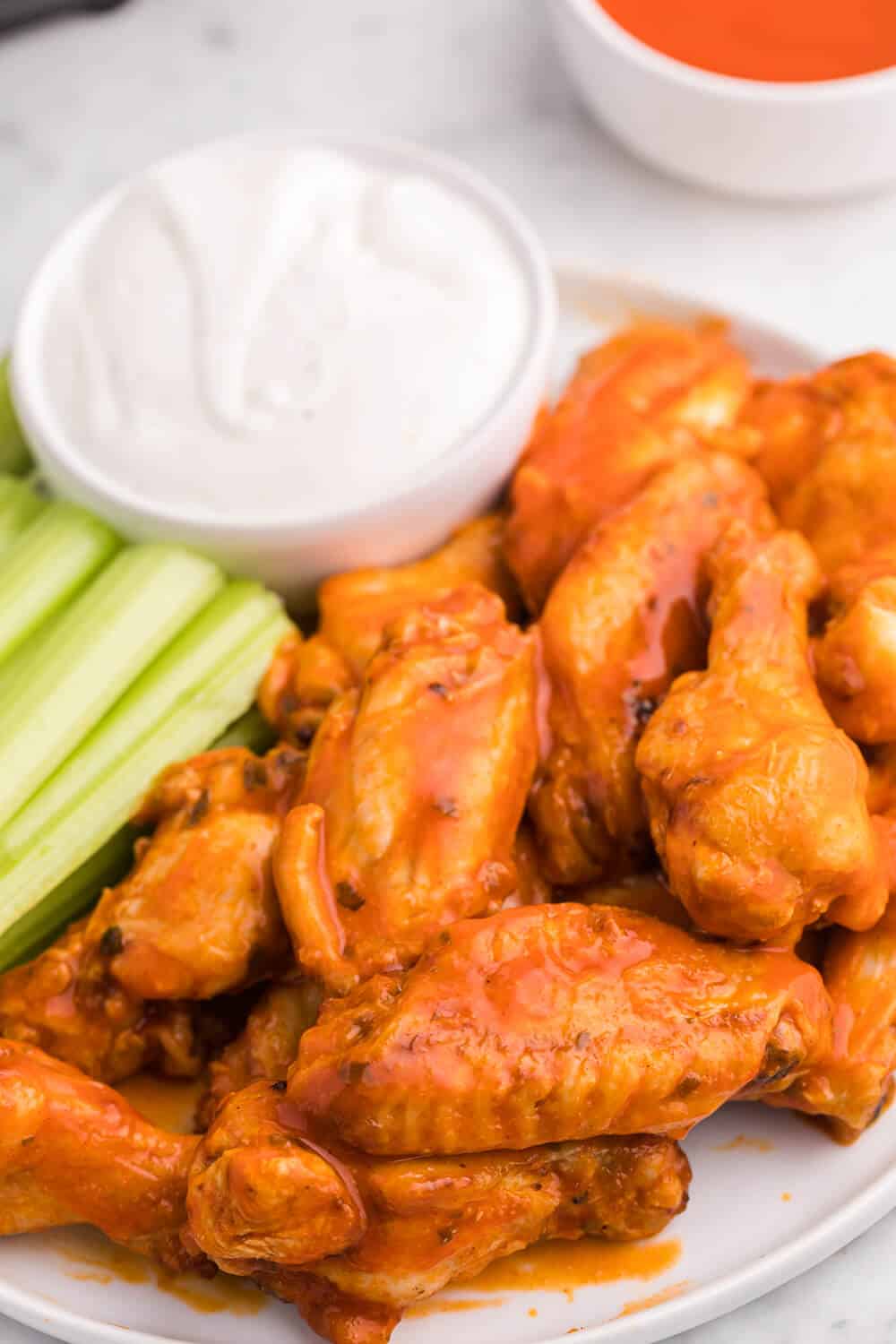 buffalo chicken wings on a plate with celery sticks and dip
