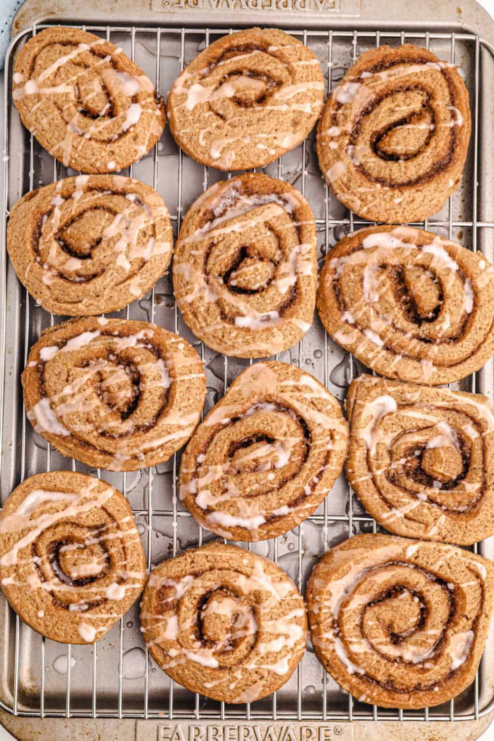 Cinnamon roll cookies on a wire rack on a baking tray