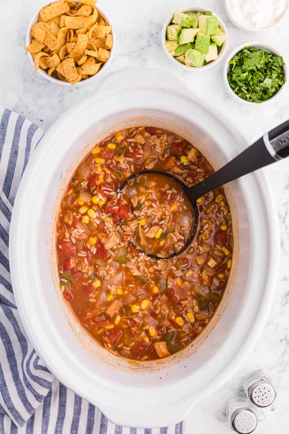 Southwest chicken and rice soup in a white slow cooker with a ladle