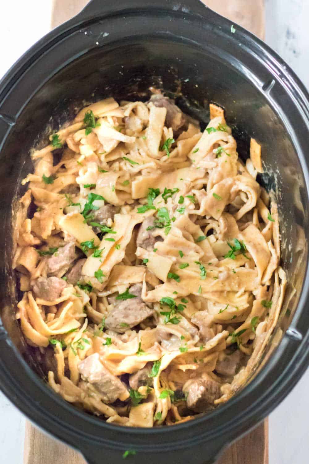 beef and noodles in a black slow cooker