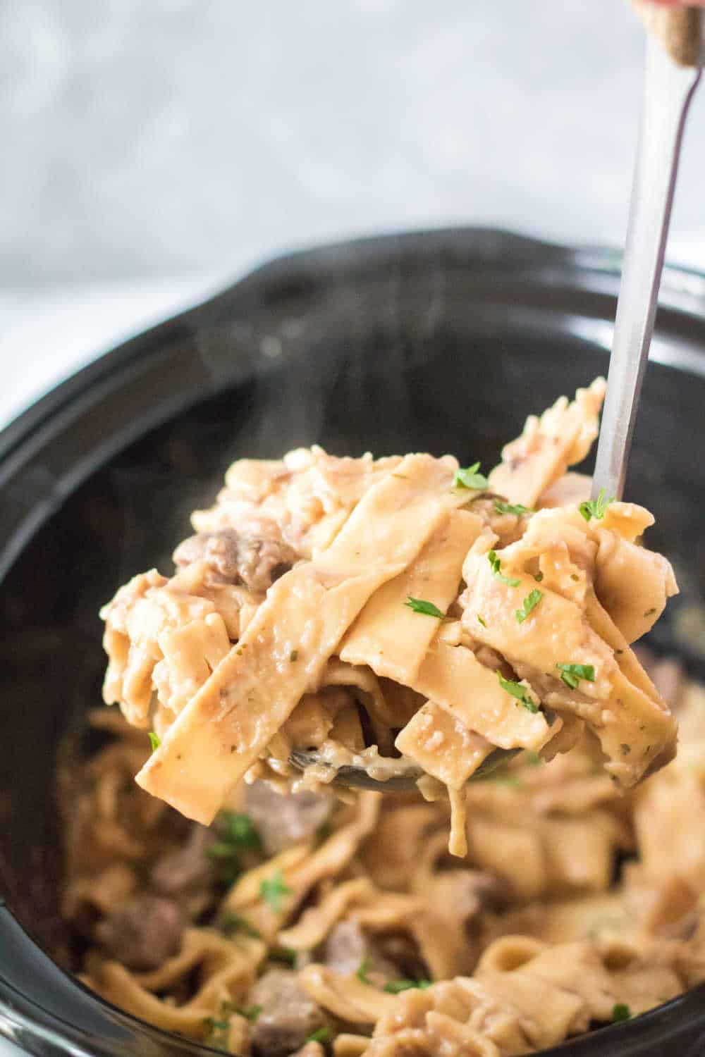 slow cooker beef and noodles on a serving spoon