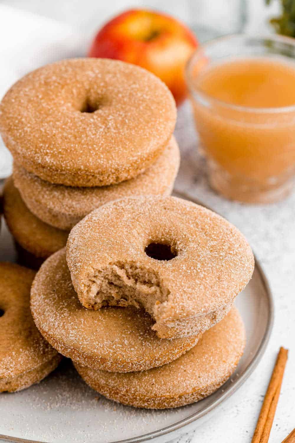 baked apple cider donuts on a plate with a bite out of one donut
