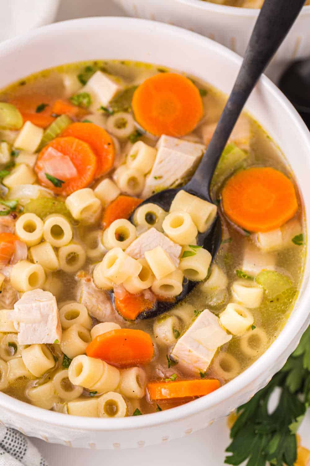 Leftover turkey soup in a white bowl and a black spoon