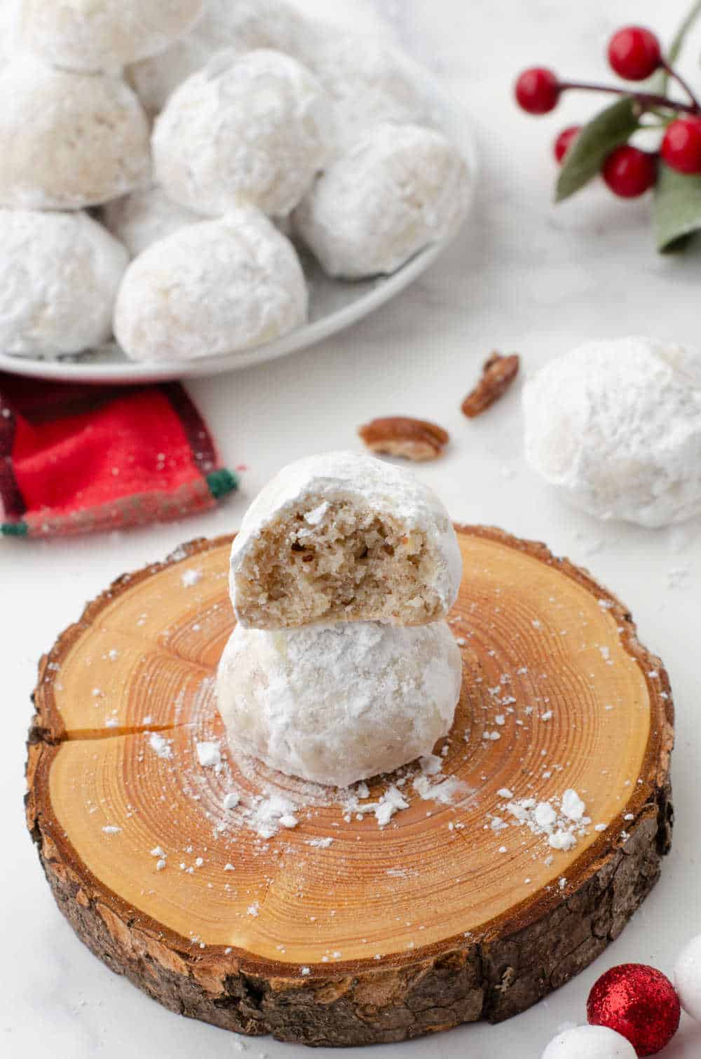 two snowball cookies stacked with the top cut in half on a wood platter
