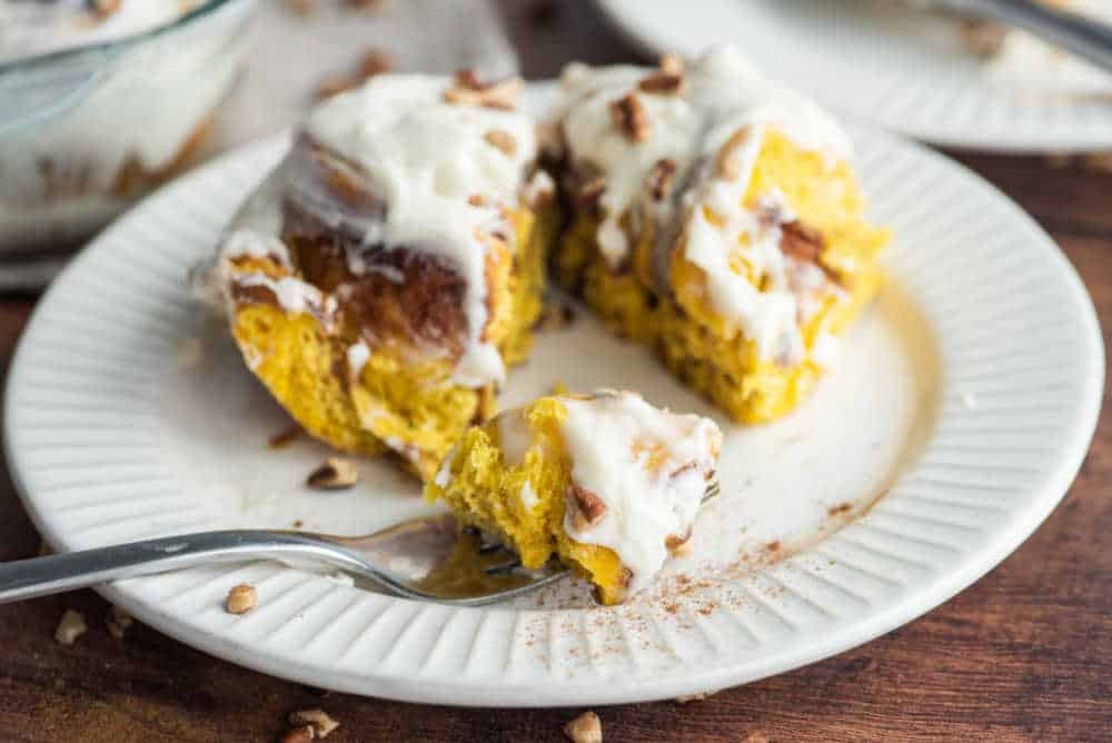 pumpkin cinnamon roll on a plate with a fork