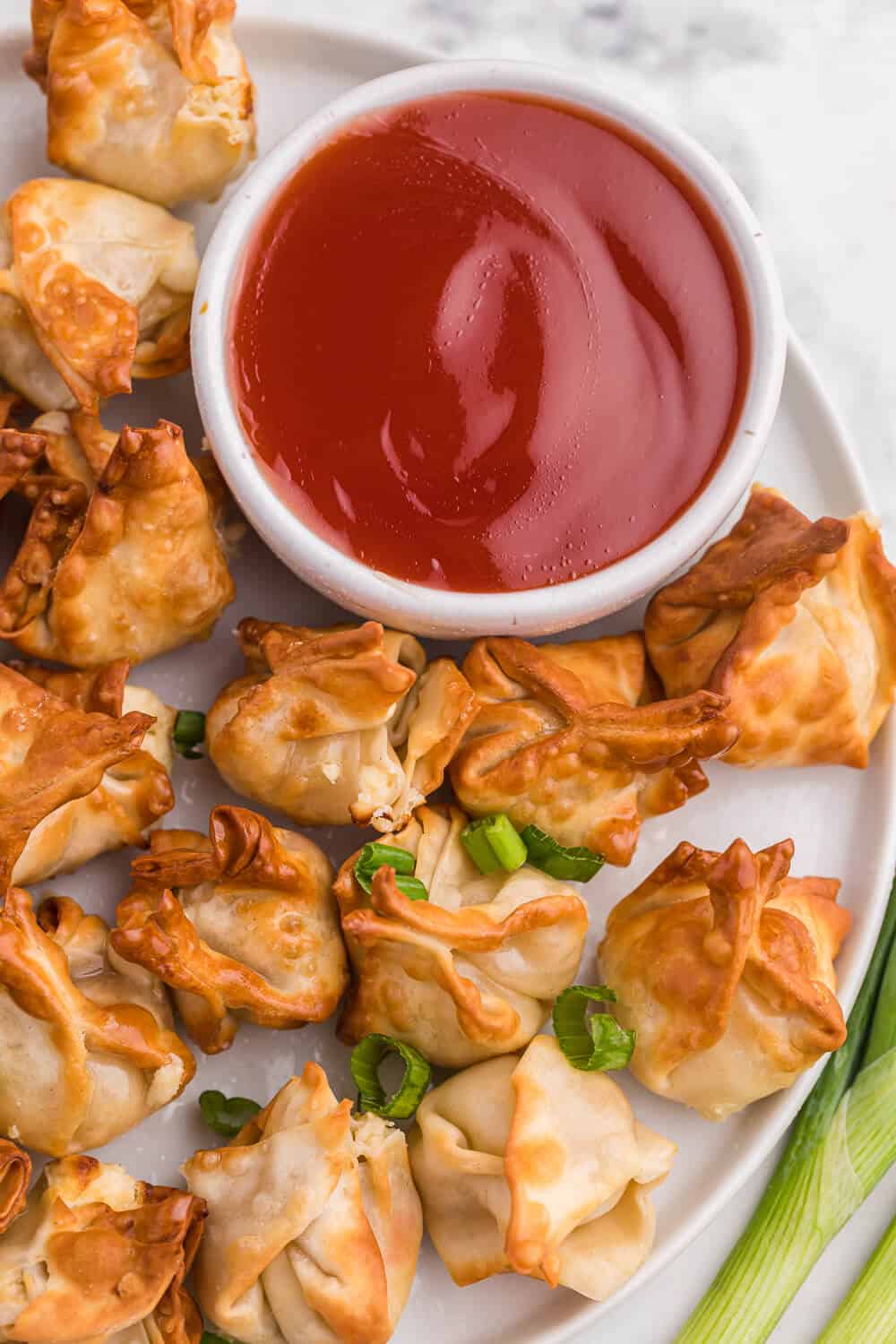 air fryer crab rangoon on a white plate with sweet and sour sauce