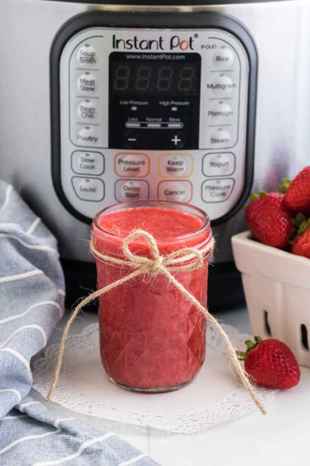 A jar of strawberry jam in front of an Instant Pot.