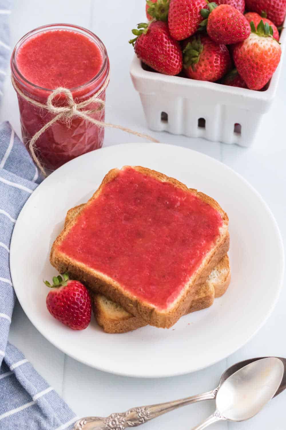 Strawberry jam on two slices of toast on a plate.