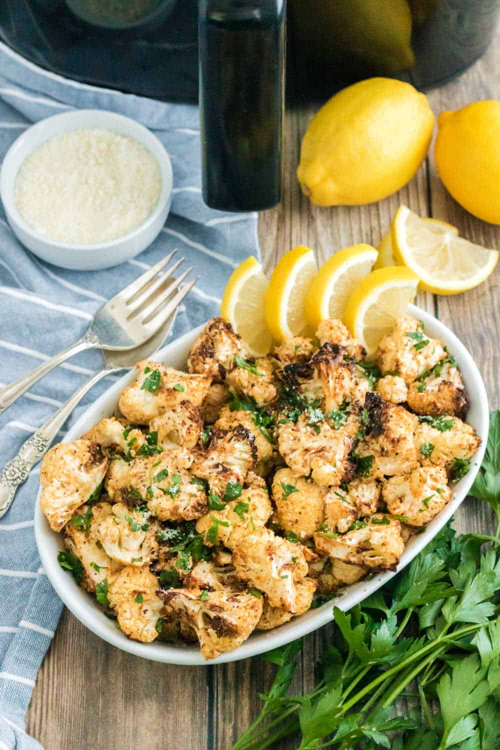 Air fryer cauliflower on a platter with lemon wedges.