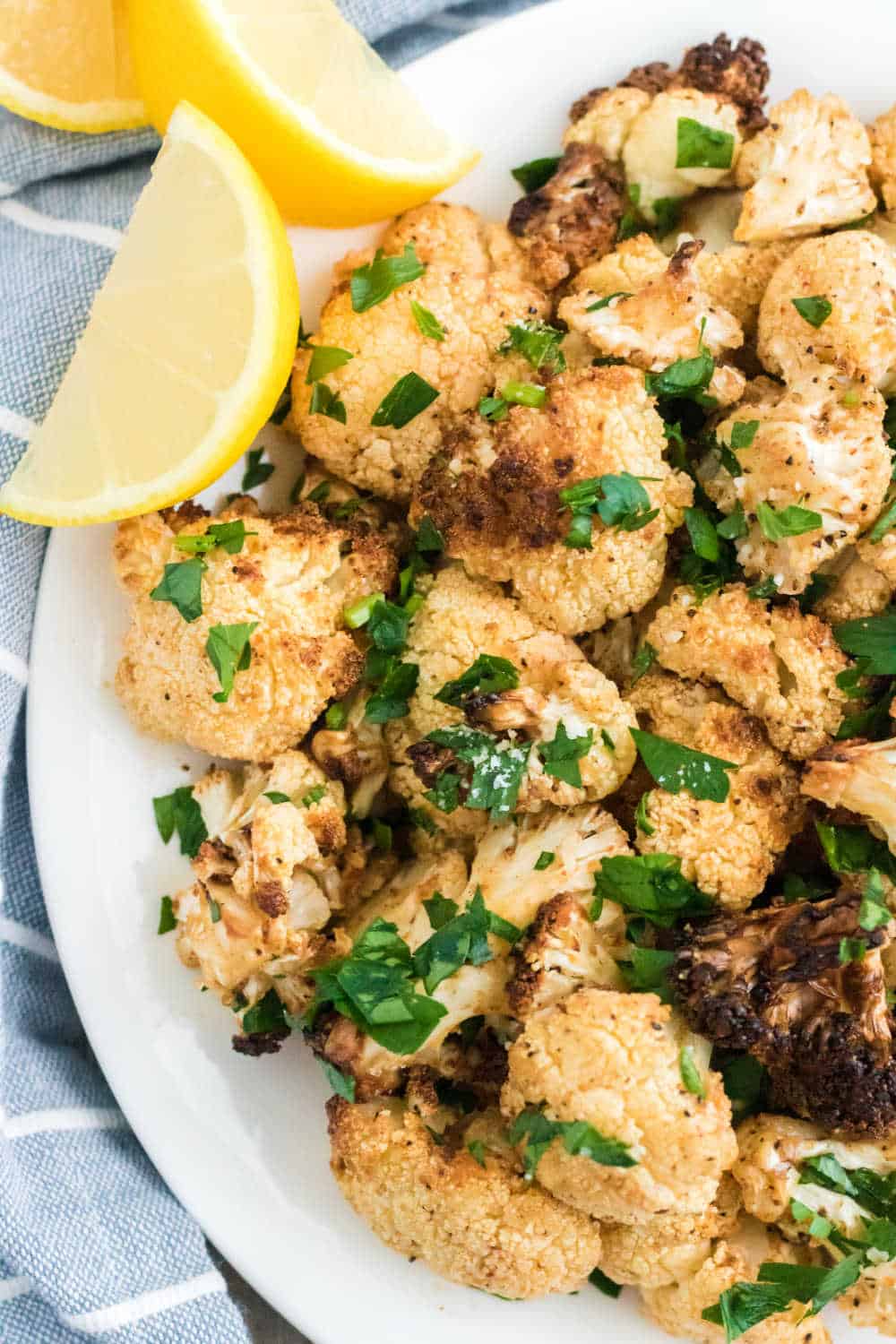 Air fryer cauliflower on a platter with lemon wedges.