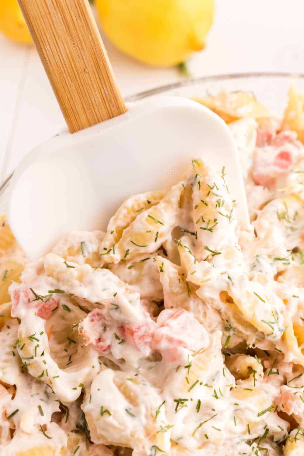 A scraper spatula in a bowl of shrimp pasta salad.