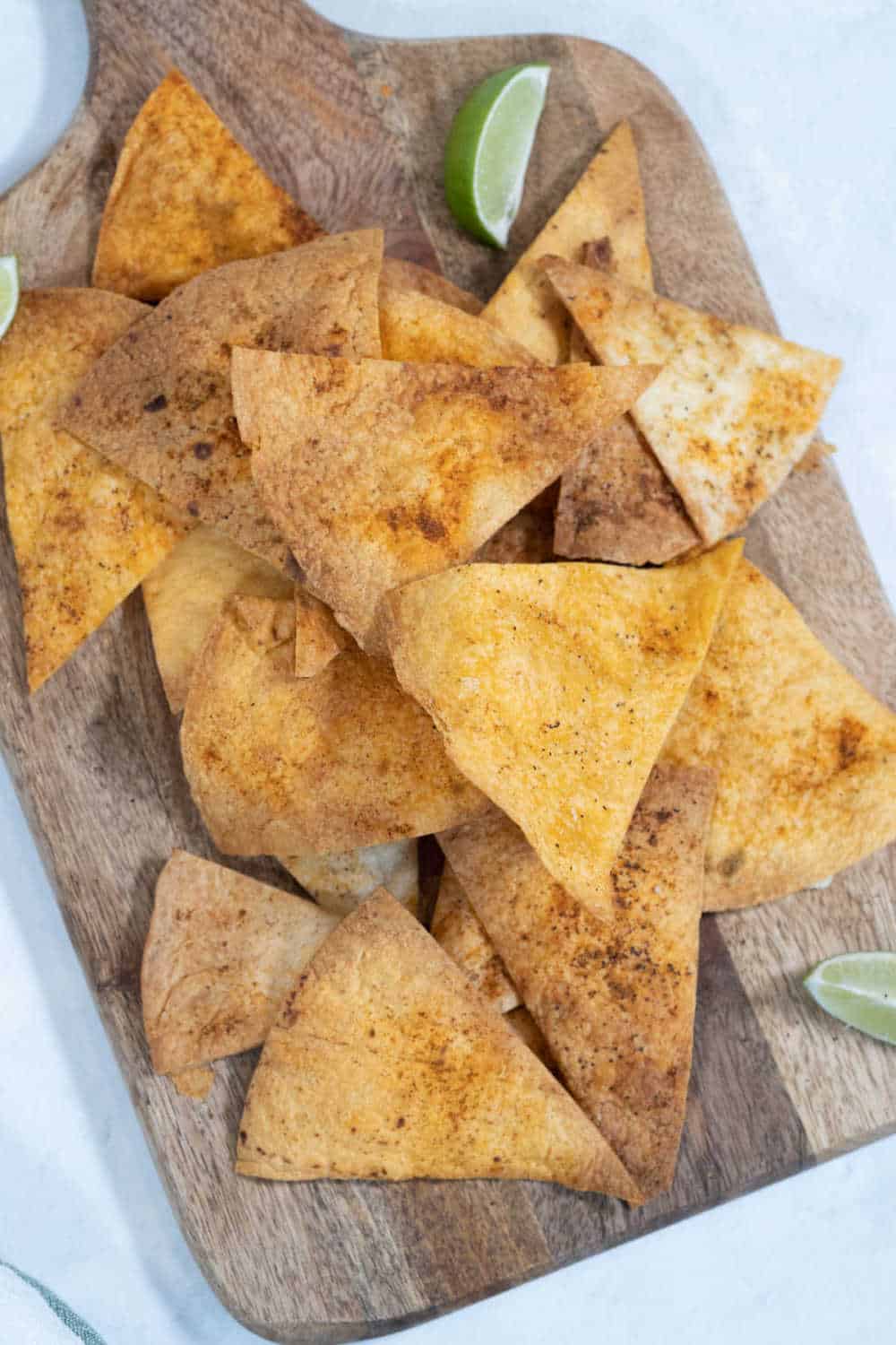 Homemade tortilla chips on a wooden cutting board.