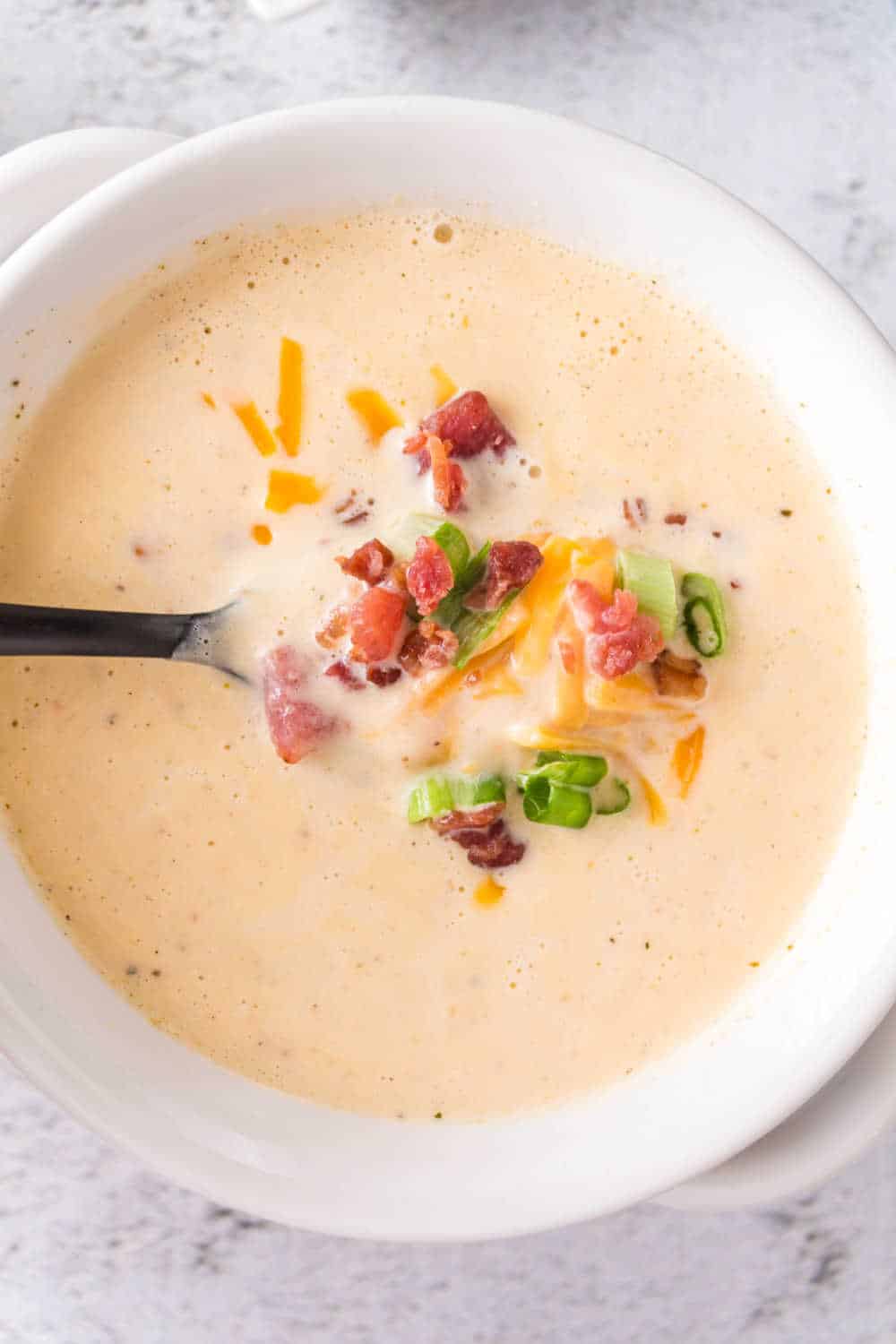 A bowl of cauliflower soup with a spoon.