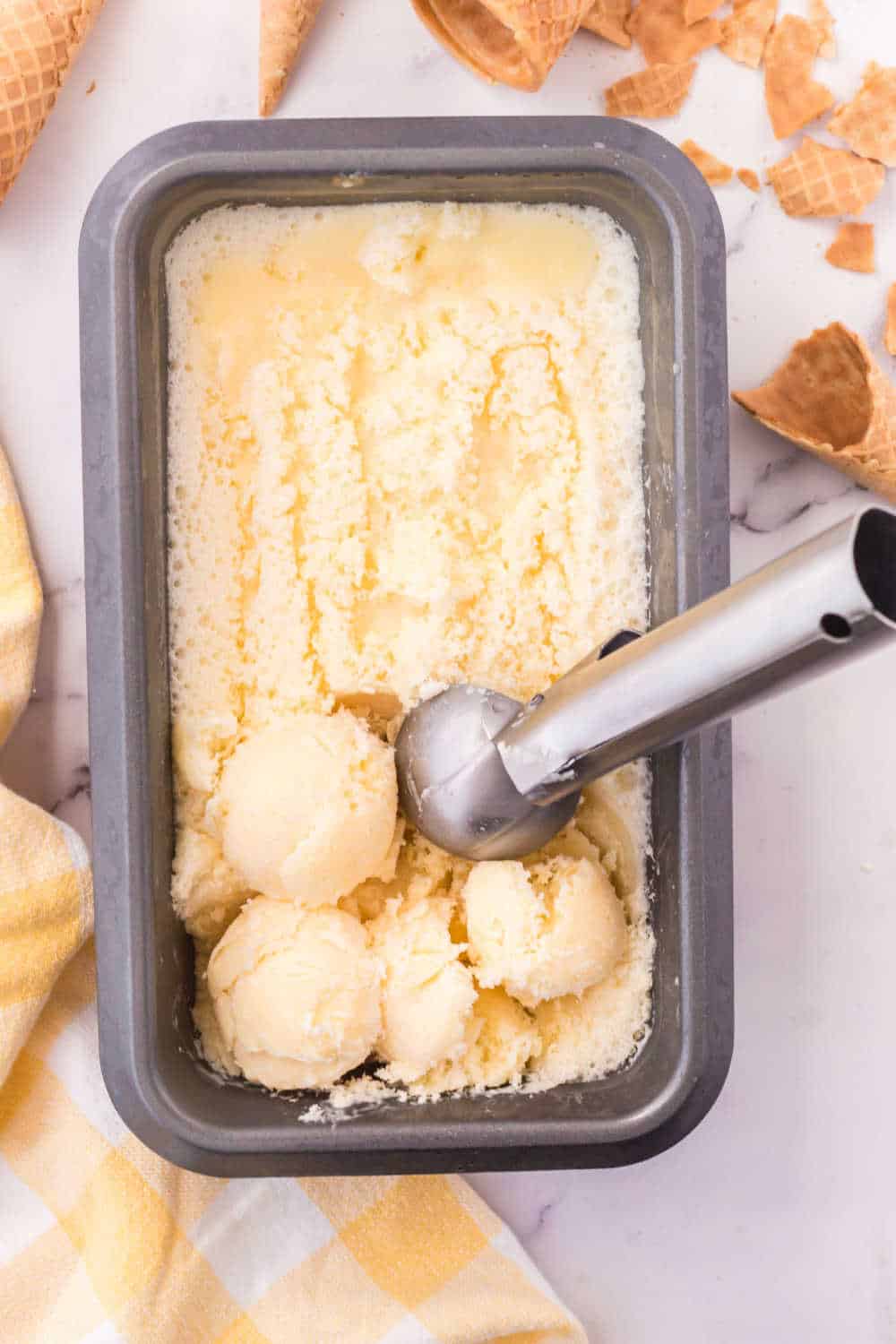 Orange sherbet in a loaf pan with an ice cream scoop.