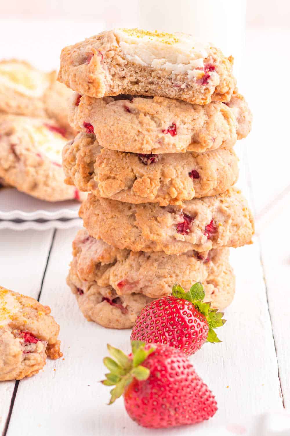 A stack of strawberry cheesecake cookies with a bite taken out of the cookie on the top.