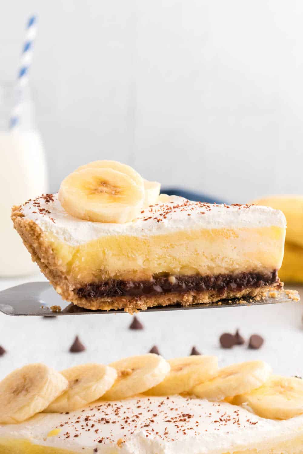 A slice of black bottom banana cream pie on a pie server.