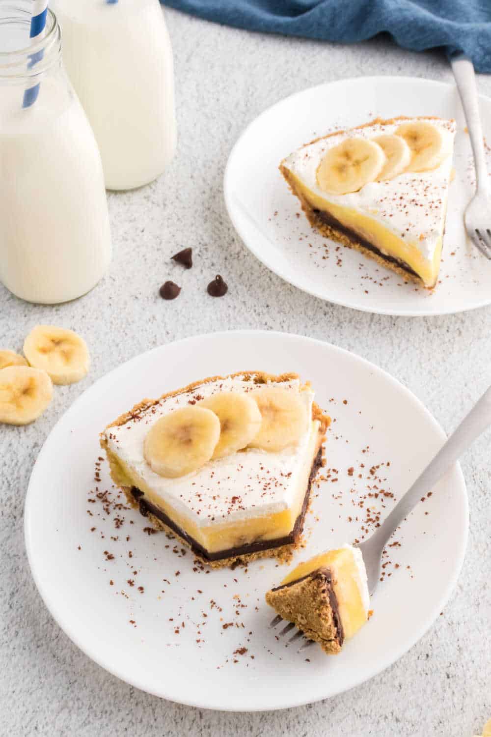 A slice of black bottom banana cream pie on a plate with a bite on a fork.