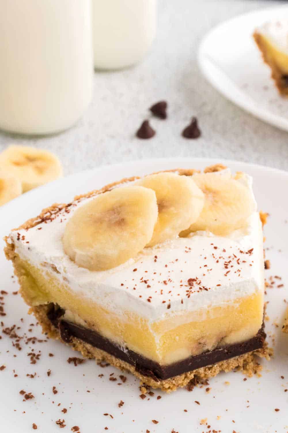 A slice of black bottom banana cream pie on a plate with a bite off the end.