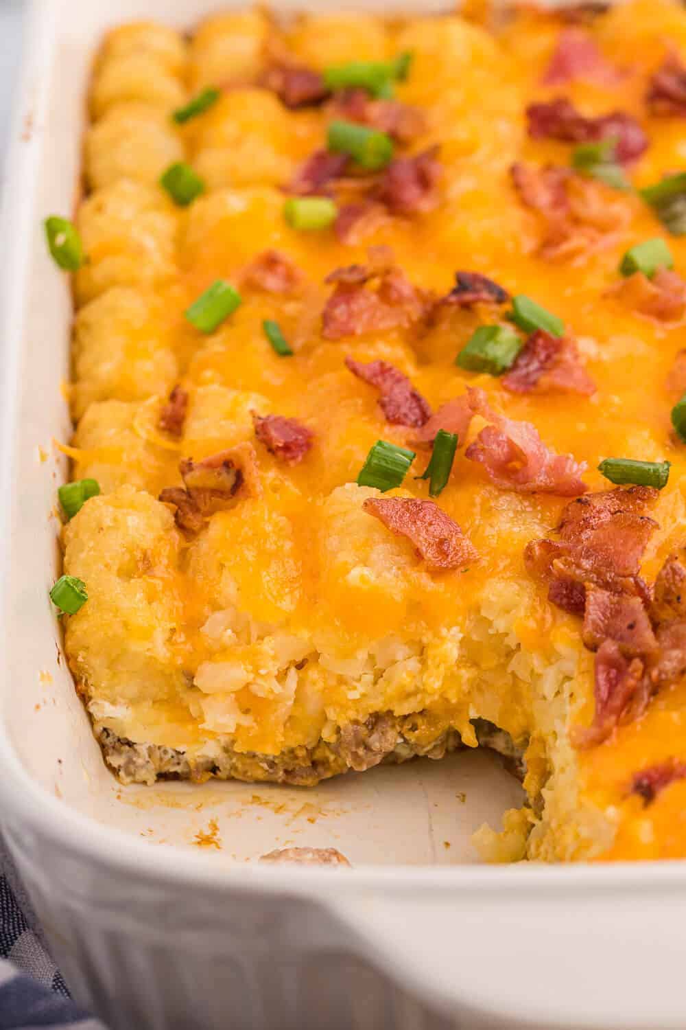 Tater tot breakfast casserole in a baking dish with a slice removed.