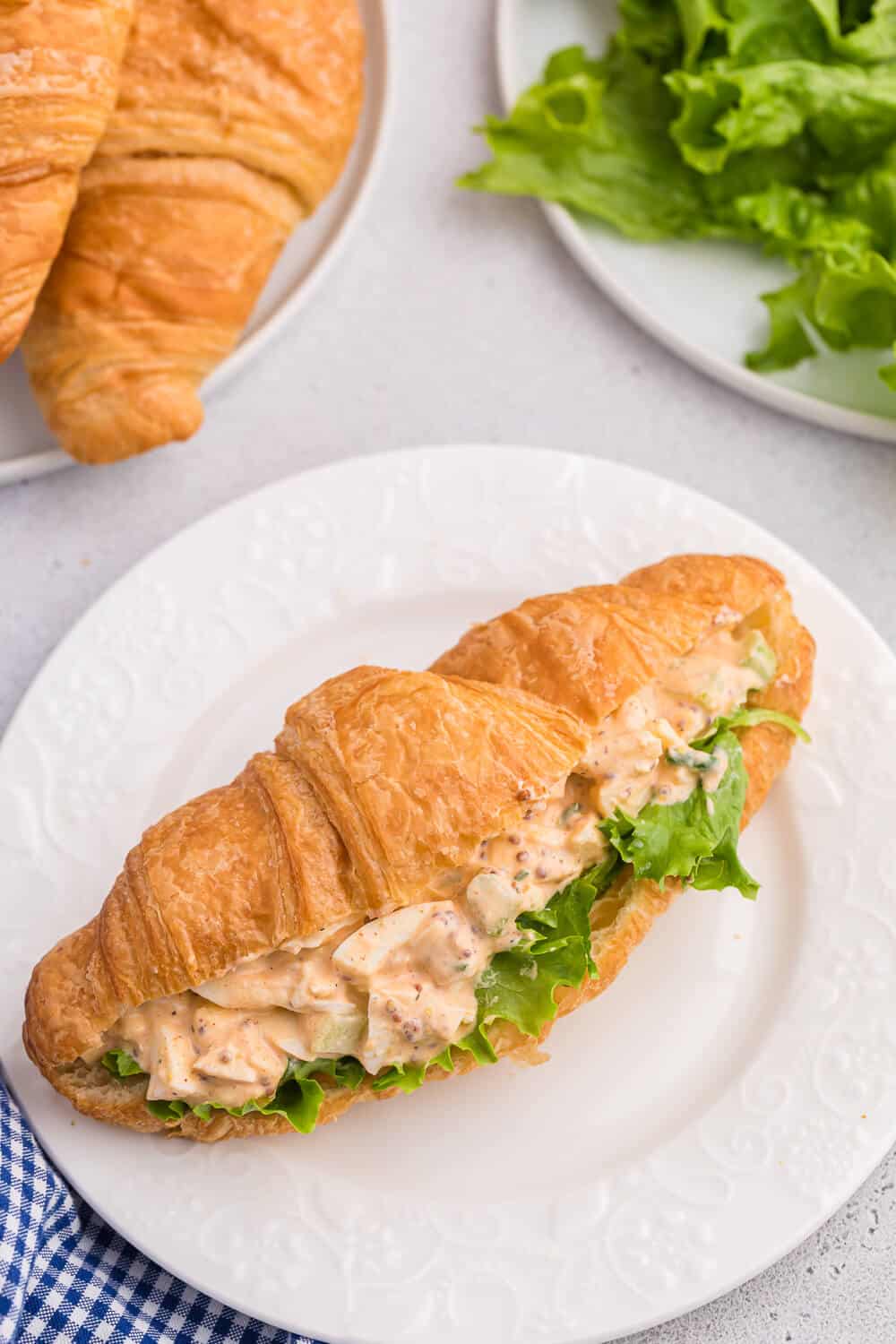 Egg salad served on a croissant with lettuce.