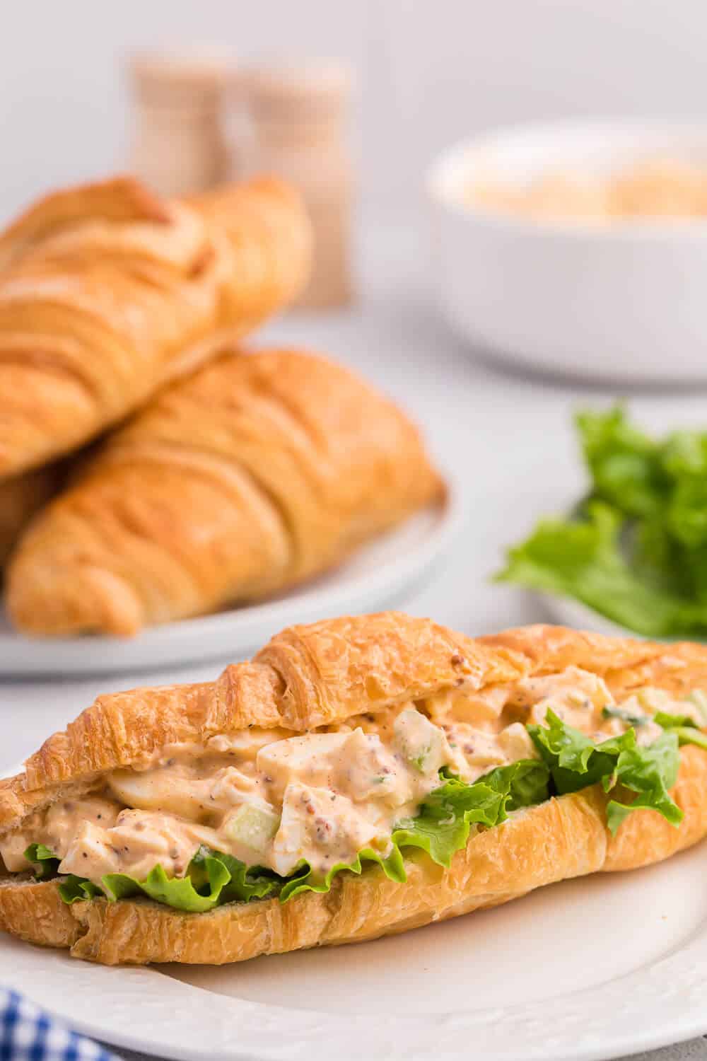 Egg salad on a croissant with lettuce.