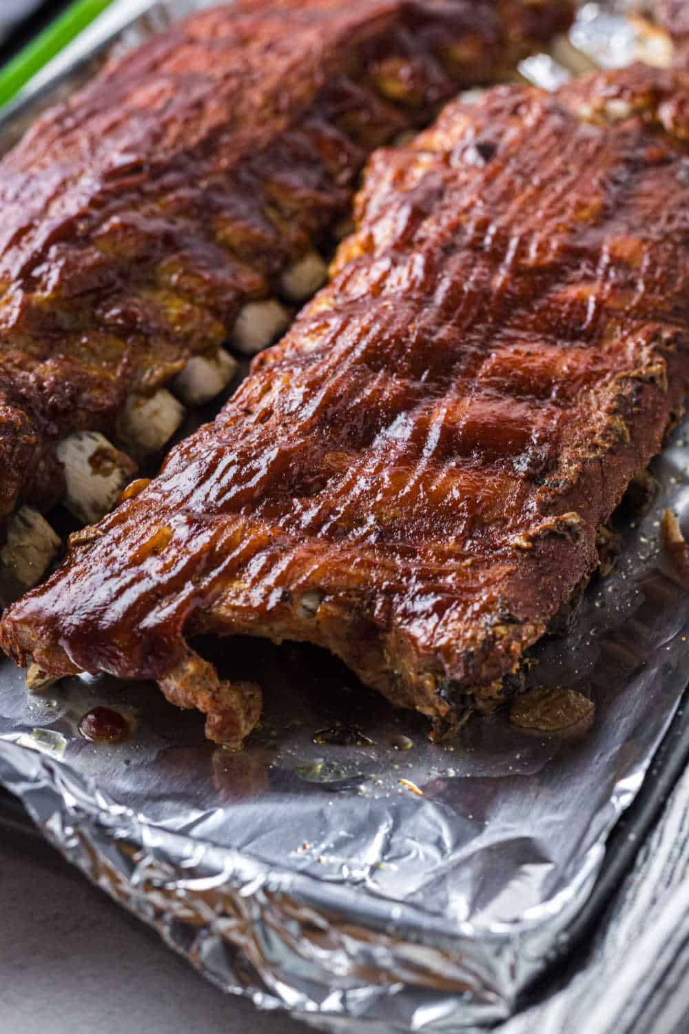 BBQ pork ribs on a baking sheet lined with aluminum foil.