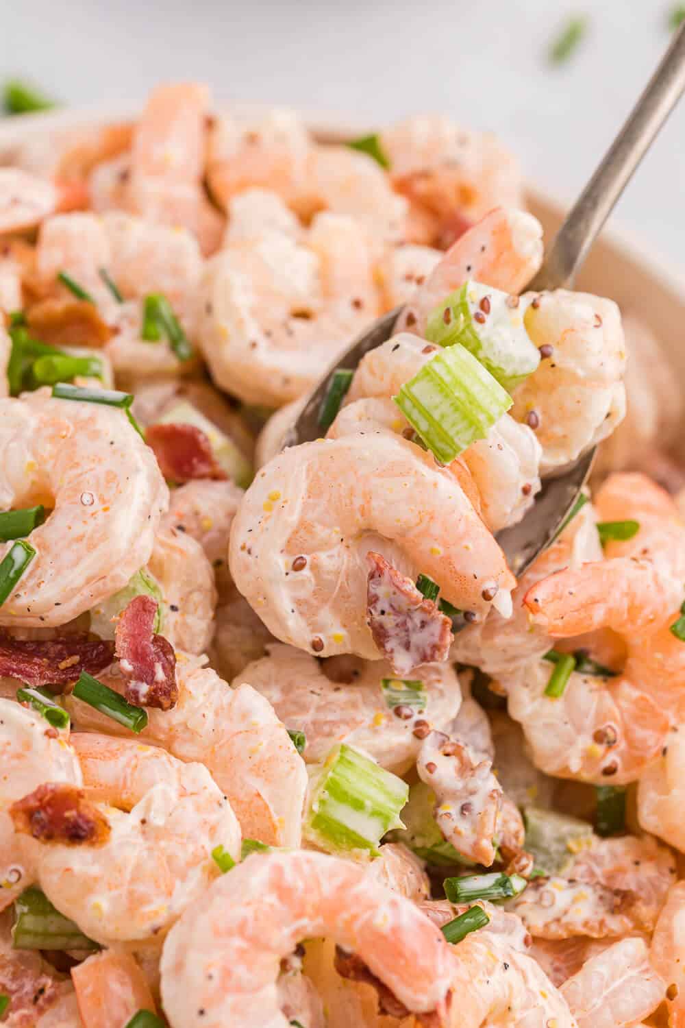 A bowl of shrimp salad with a spoon.