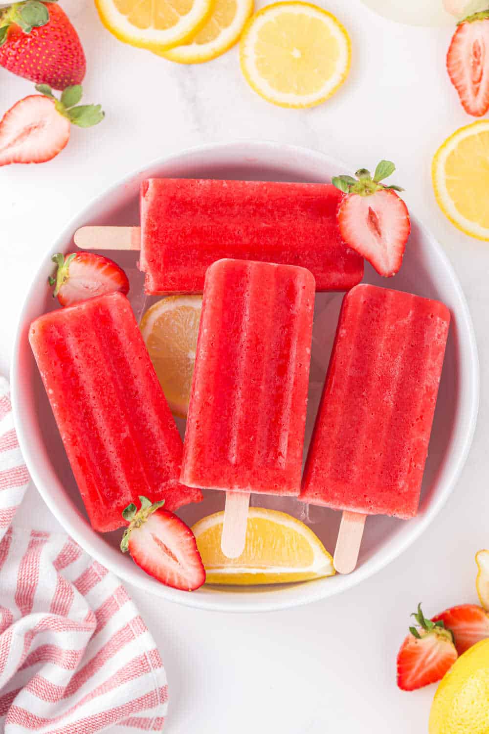 Strawberry lemonade popsicles in a bowl of ice.