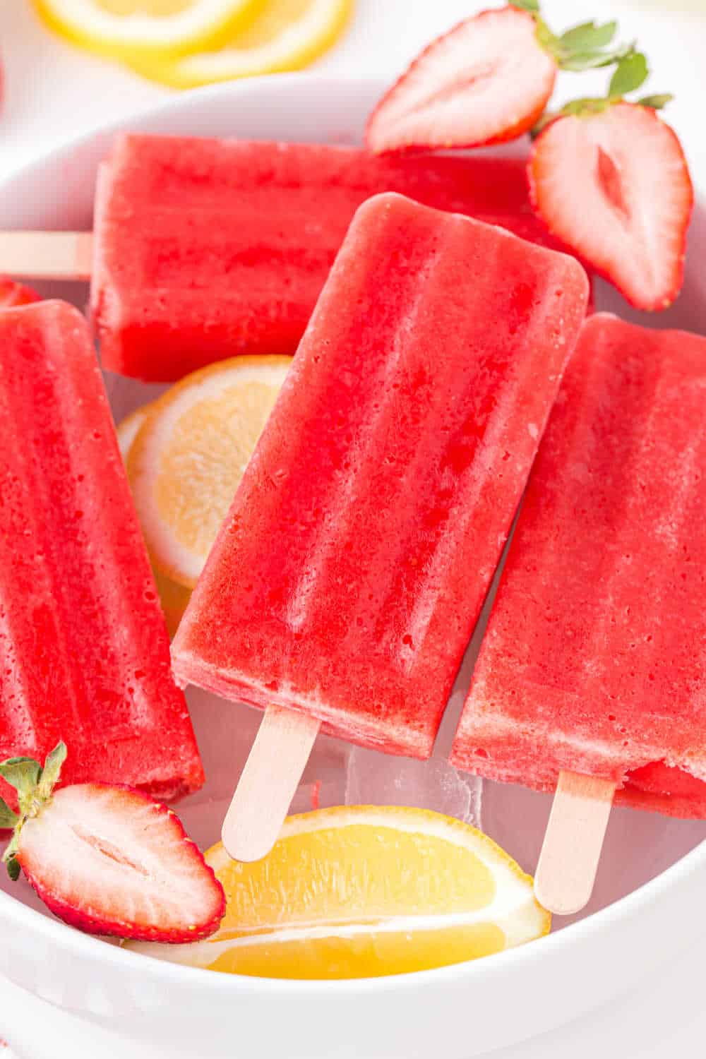 Strawberry lemonade popsicles in a bowl of ice.