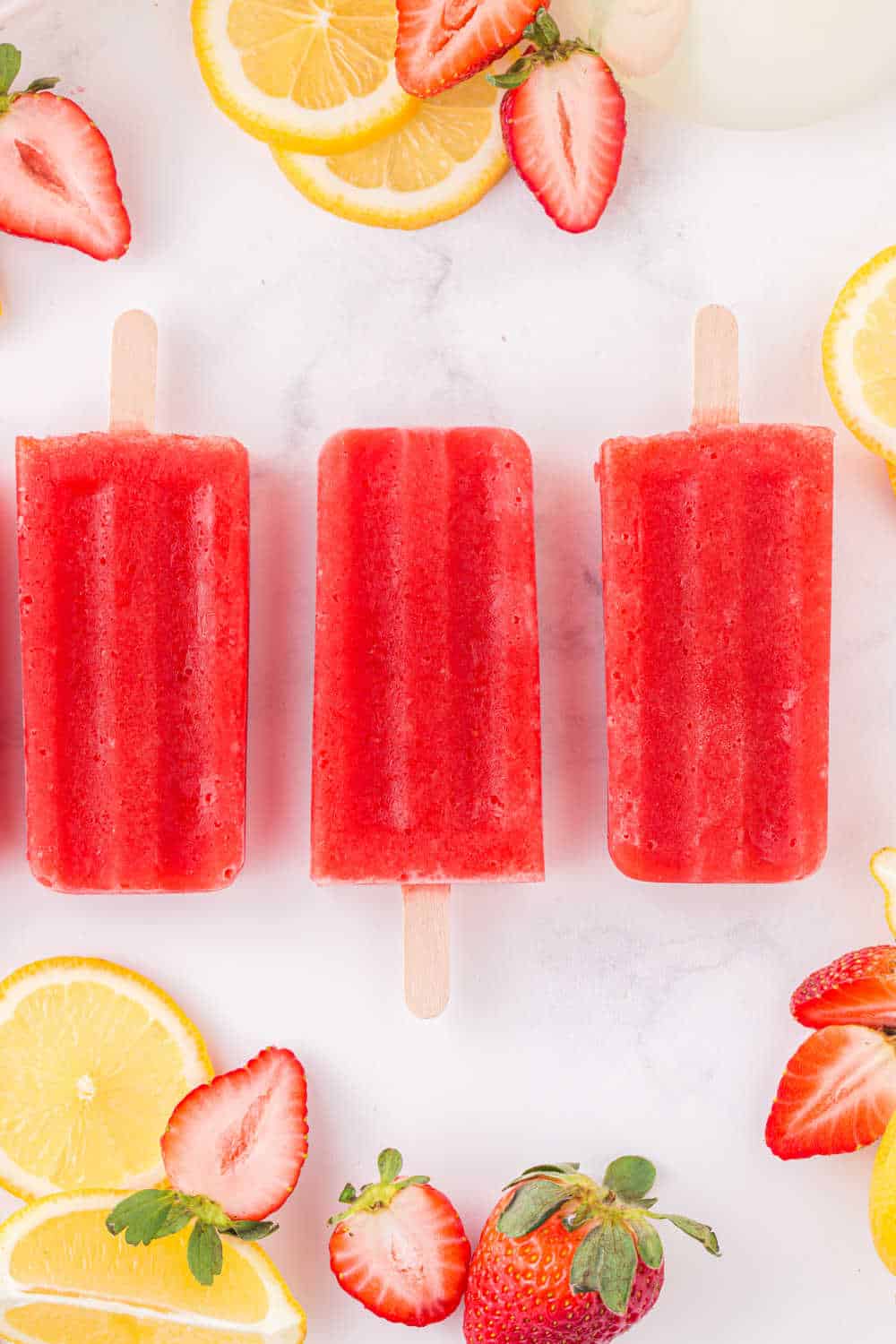 Strawberry lemonade popsicles laid out on a flat surface.