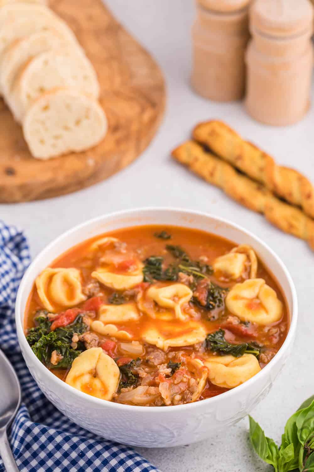 Tortellini soup in a white bowl.