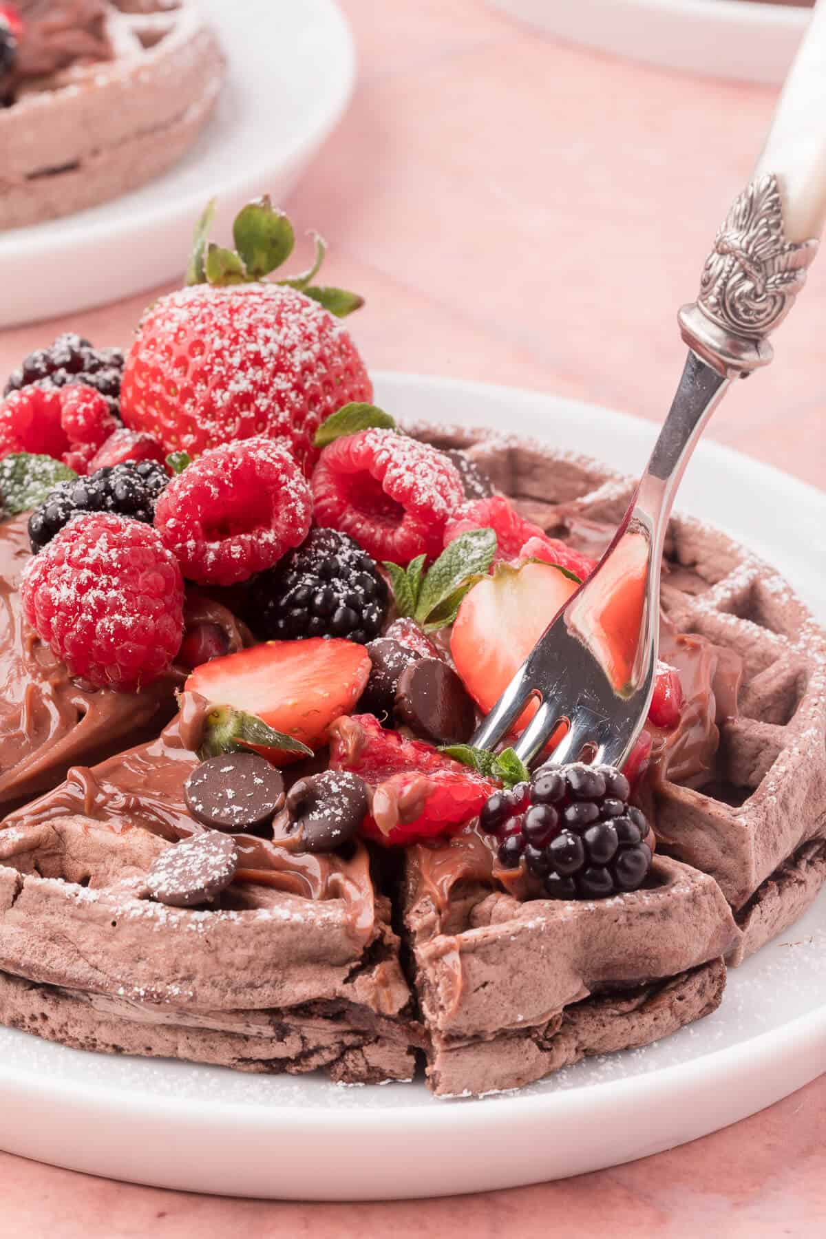 A plate of chocolate waffles with a fork in them.