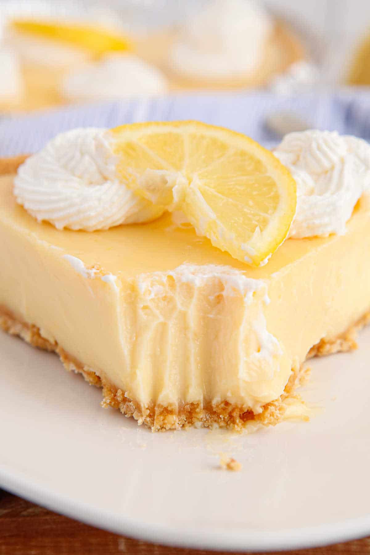 Classic lemon pie slice on a plate with a bite off the tip.