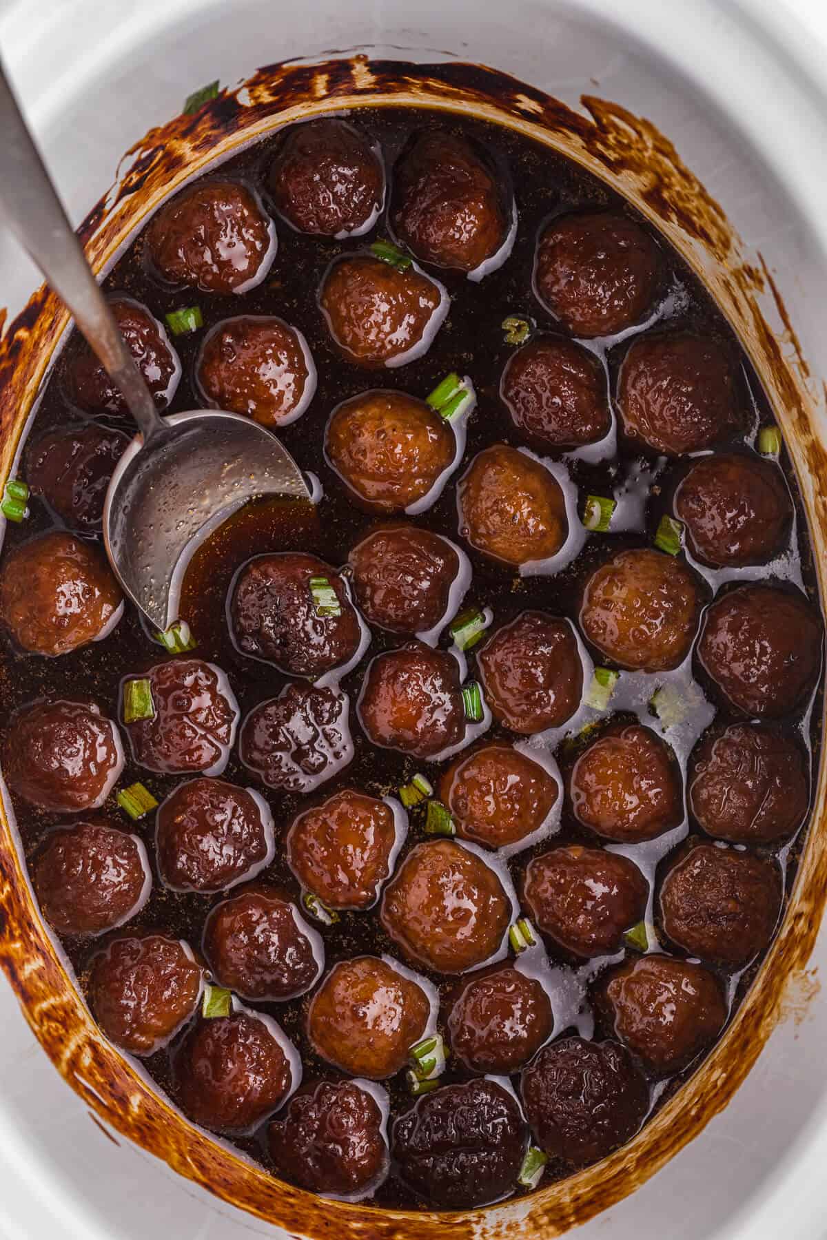 Grape jelly meatballs in a crockpot with a serving spoon.