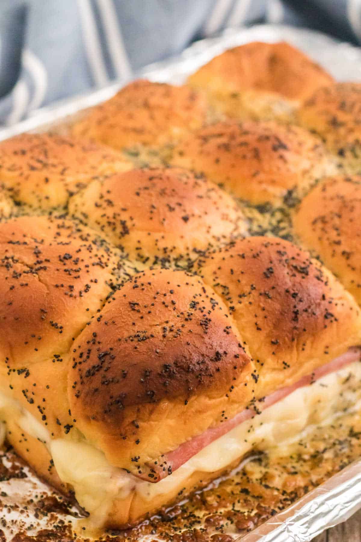 A slab of ham and cheese sliders on a baking tray.