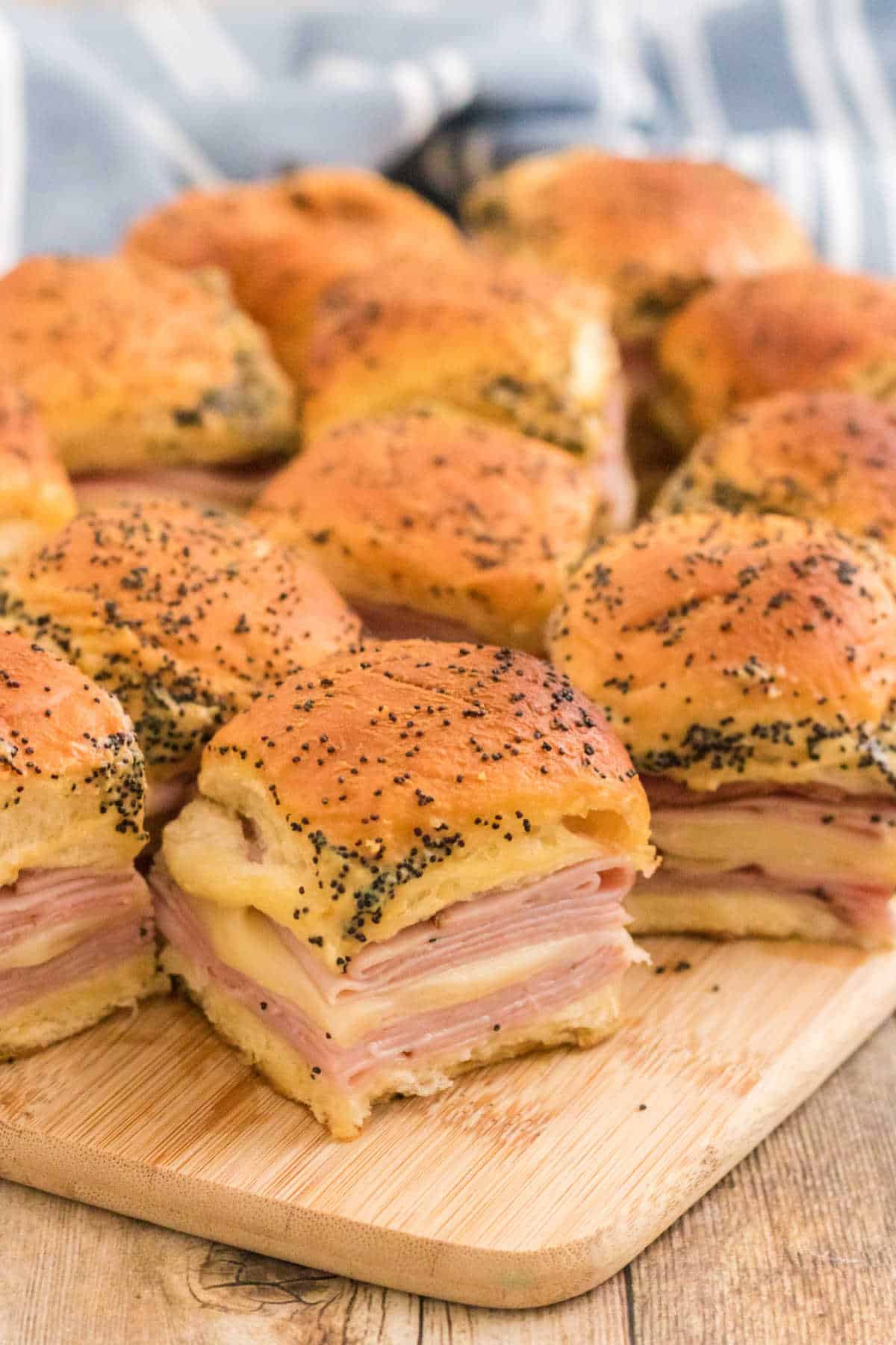 Ham and cheese sliders on a wooden cutting board.