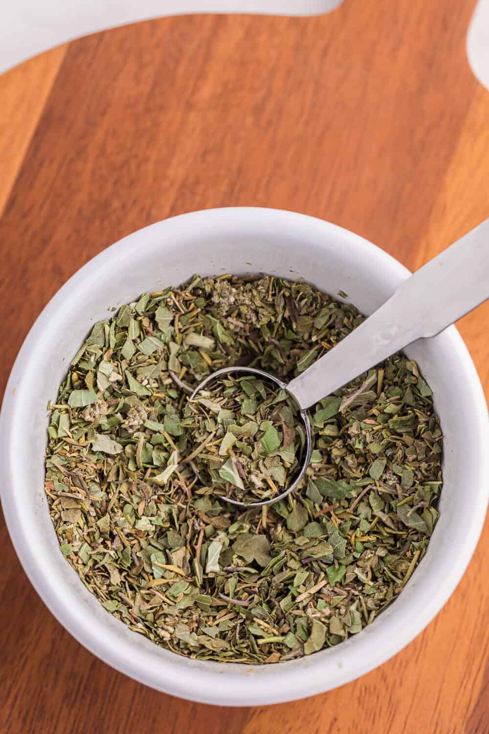 Italian seasoning in a bowl with a measuring spoon.