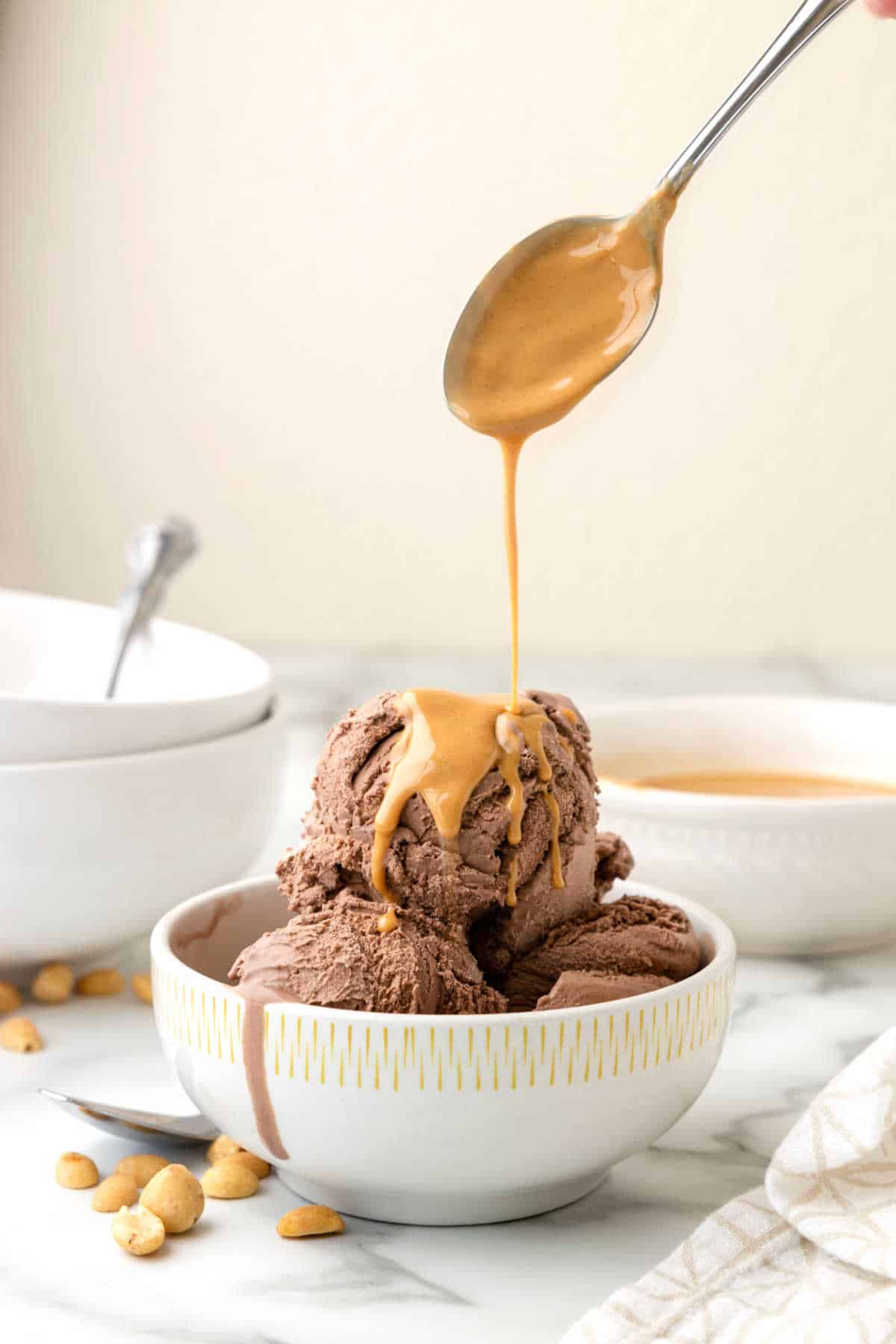 Peanut butter magic shell being drizzled on chocolate ice cream with a spoon.