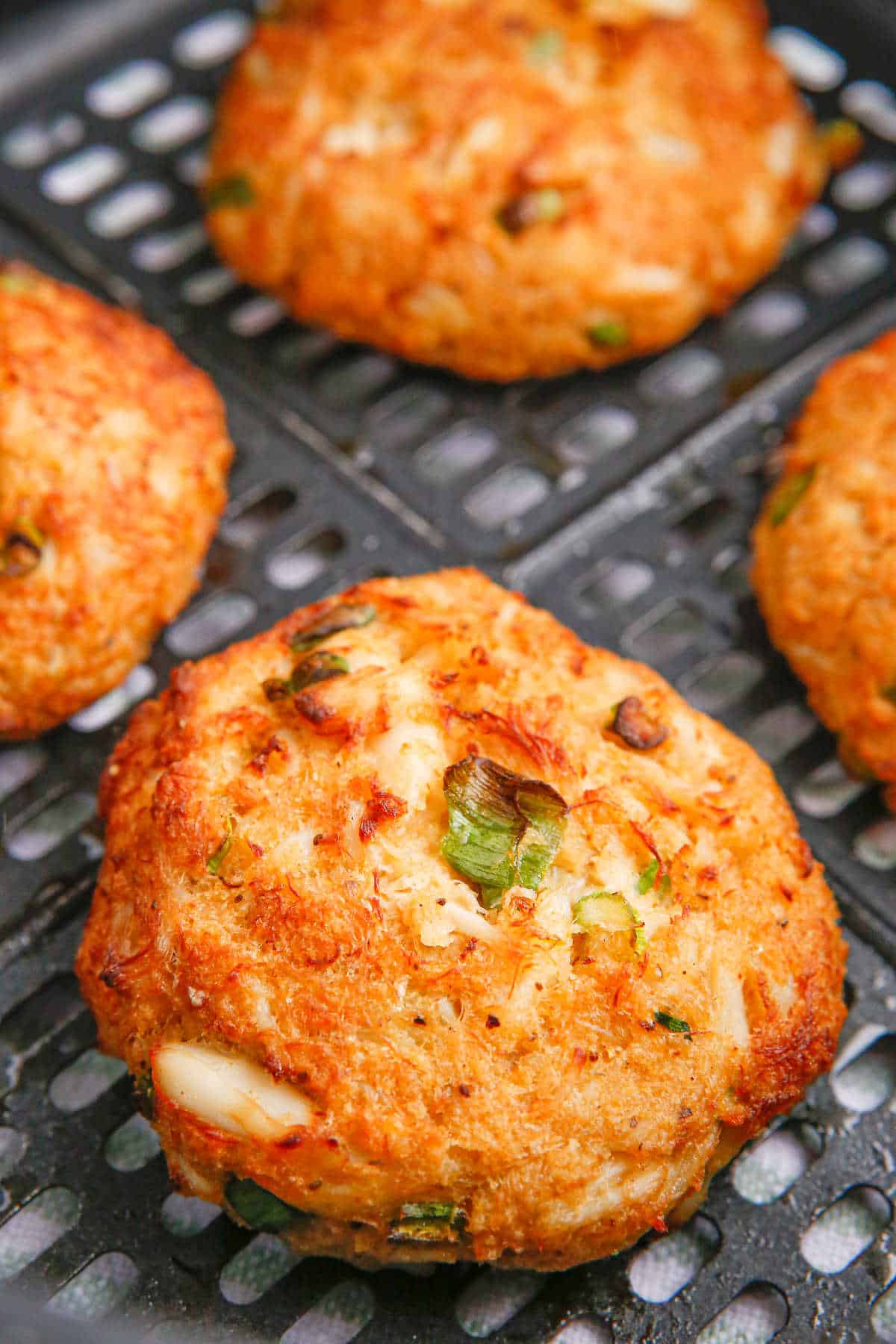 Crab cakes in an air fryer basket.