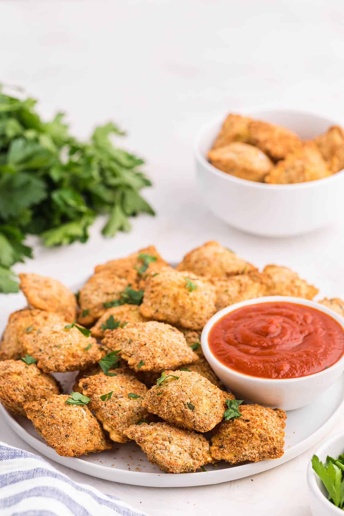 Air fryer ravioli served on a plate with marinara sauce.